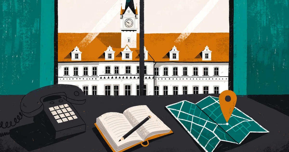 Schreibtisch mit Telefon, Notizbuch und Stadtplan mit einer Markierung, im Fenster das Rathaus